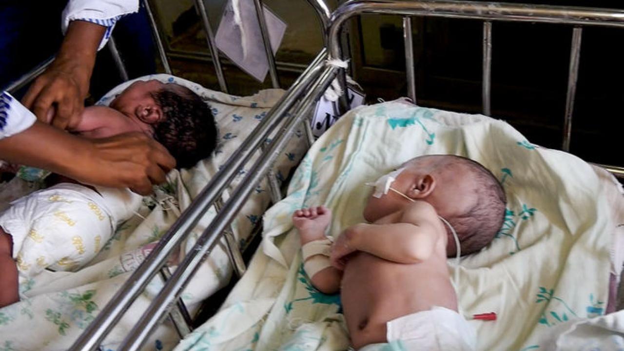 2 babies in hospital cribs, side-by-side, recovering after surgery for spina bifida.