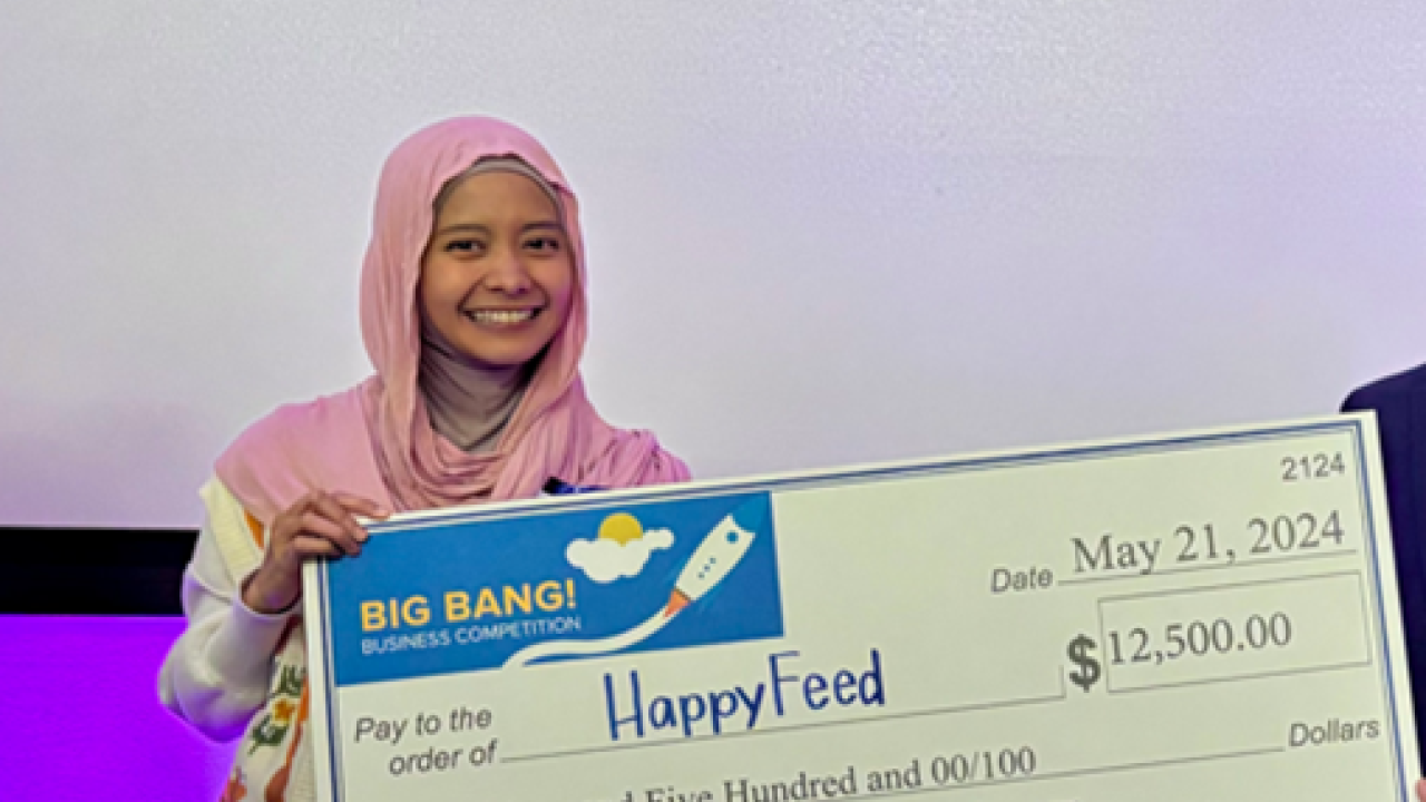Davrina. on stage holding BigBang! Awards 12,500 check.