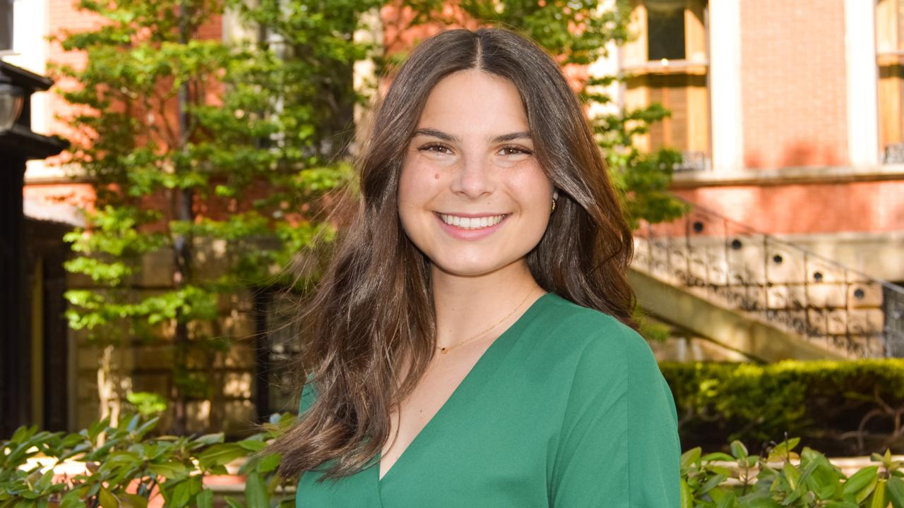 Lauren Thompson profile photo, green dress, bushes, garden background