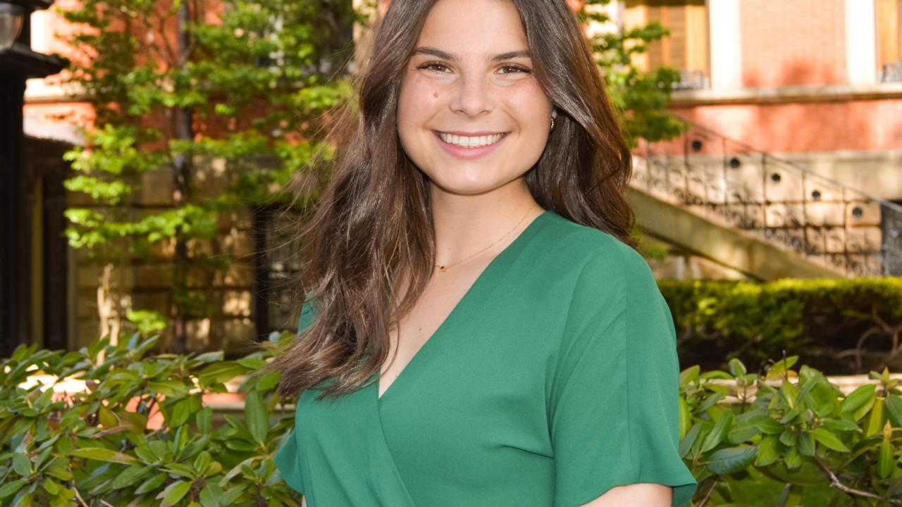 Lauren Thompson profile photo, green dress, bushes, garden background