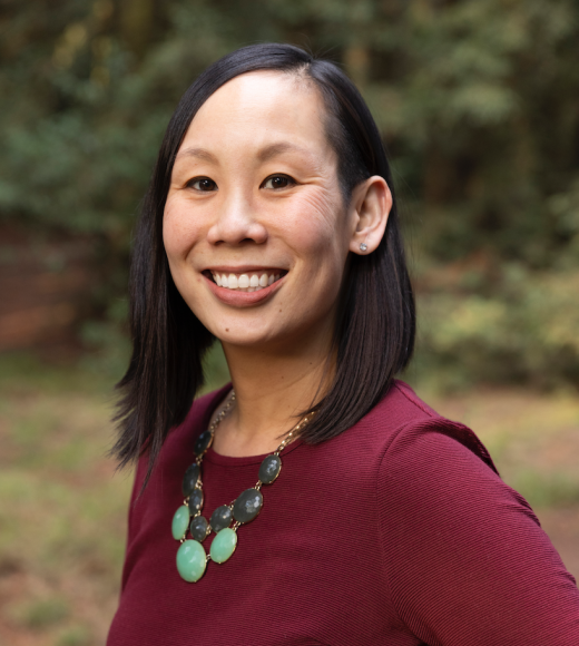 Lauren Au, profile photo, smiling face in burgundy dress, & big round jade stone necklaces