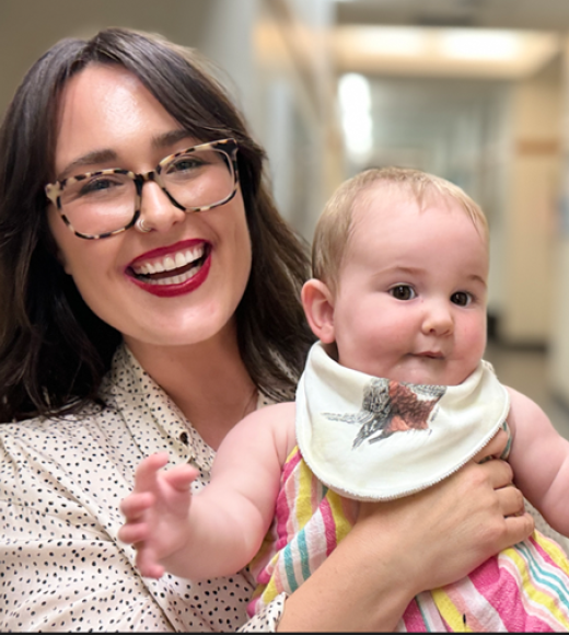 Lindsey Partington smiling holding chubby baby with bib