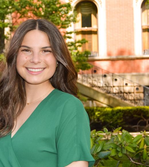 Lauren Thompson profile photo, green dress, bushes, garden background