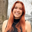 Madelyn smiling, in black sleeveless knit top; w/ long auburn hair