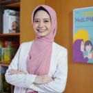 Davrina Rianda profile photo, smiling with pink head scrarf, white top, arm folded