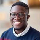 Manny Gyimah profile photo in navy blue & burgundy striped sweater