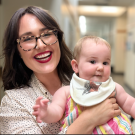 Lindsey Partington smiling holding chubby baby with bib